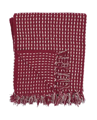 Een gevouwen rode plaid met een wit steekpatroon en kwastjes aan de randen.