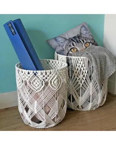 Two decorative macrame wire baskets hold a blue yoga mat, a cosy grey blanket and a cat-print cushion.