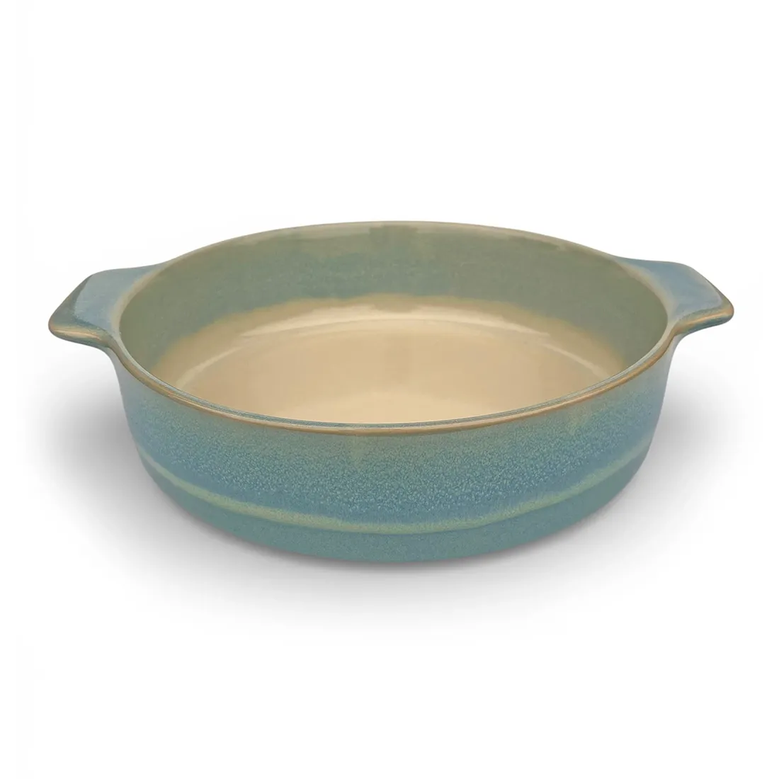 A round oven dish in a reactive glaze of blue hues, featuring two curved handles and a smooth interior.