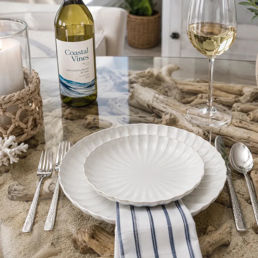 White dinner plate setting, with silverware, a bottle and glass of white wine.