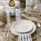 White side plate setting, with silverware, a bottle and glass of white wine.