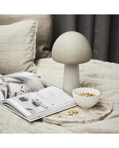 A dessert bowl with nuts sits on a marble tray beside a mushroom lamp.