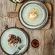 A rustic wooden table features two bohemian dinner plates.
