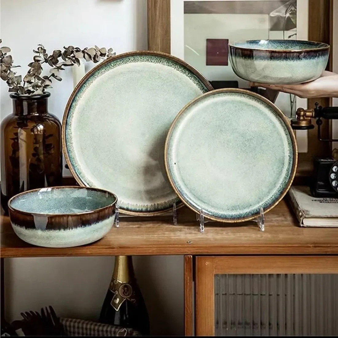 Een collectie van het bohemien dinerbord in aardetinten, waaronder borden en een kom, uitgestald op een houten plank.