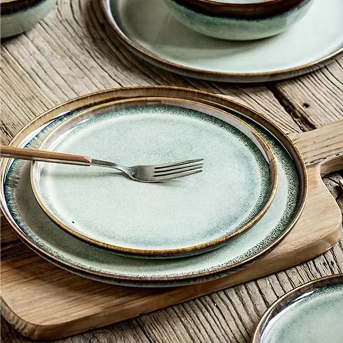 A set of elegant bohemian dinner plates with a reactive glaze, on a rustic wooden table.