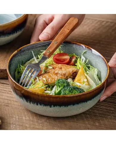 A close-up of a bohemian soup bowl filled with salad, chicken, and broccoli, with a fork resting beside.