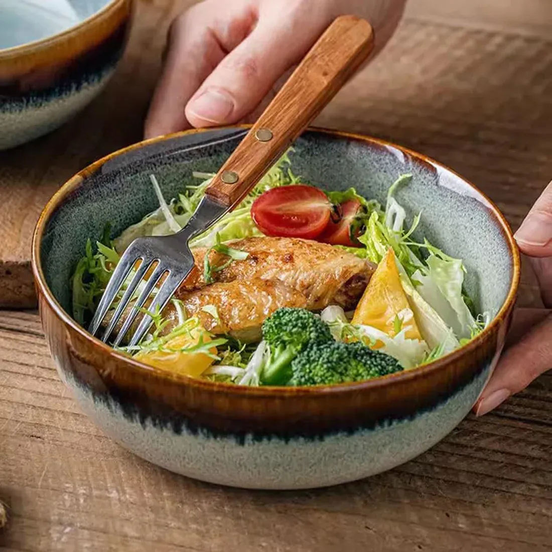 Een close-up van een bohemien soepkom gevuld met salade, kip en broccoli, met een vork ernaast.