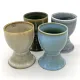 Four assorted ceramic egg cups with a reactive glaze finish.