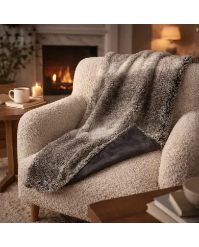 Cosy armchair with a soft grey faux fur throw blanket in a warm living room with a lit fireplace.