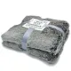 Opgevouwen grijze plaid van imitatiebont, opgevouwen met een zilveren lint en voorzien van het merklabel Lavandoux.