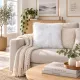 Bright, cosy living room with a beige sofa, white faux fur cushion and coffee table books.