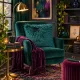 Cosy jewel-toned reading nook with teal velvet armchair and a teal faux fur cushion.