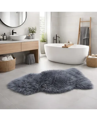 Modern bathroom with a freestanding white tub and a plush grey sheepskin rug on a tile floor.