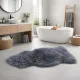 Modern bathroom with a freestanding white tub and a plush grey sheepskin rug on a tile floor.
