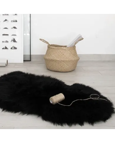 Black sheepskin rug, beside a woven basket holding rolled papers.