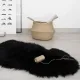 Black sheepskin rug, beside a woven basket holding rolled papers.