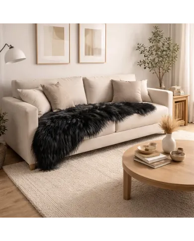 Cosy neutral living room with a cream sofa and a black sheepskin rug draped over it.