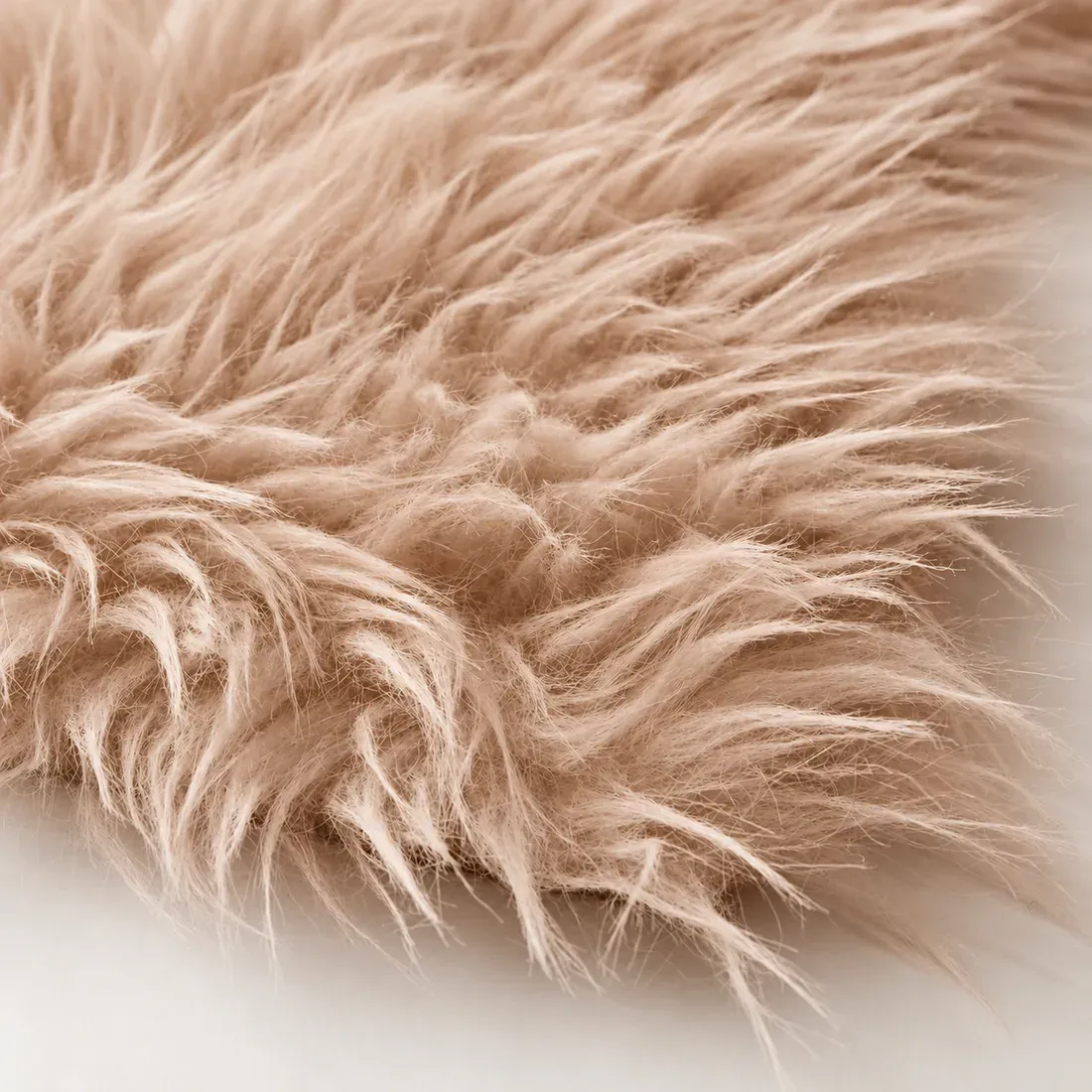 Close-up of a soft, fluffy beige faux fur sheepskin rug.