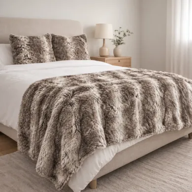 Knusse slaapkamer met een taupekleurige bont plaid op het bed en bijpassende exemplaren van het imitatie bont kussen.