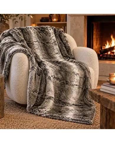 Cosy armchair with a soft grey faux fur throw blanket in a warm living room with a lit fireplace.