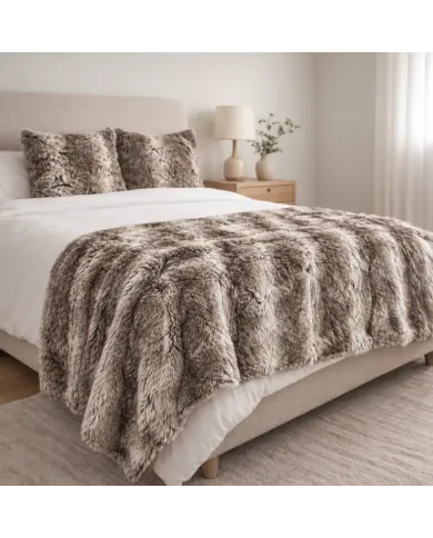 Cosy bedroom with a taupe faux fur throw on the bed and matching fur cushions.