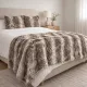 Cosy bedroom with a taupe faux fur throw on the bed and matching fur cushions.