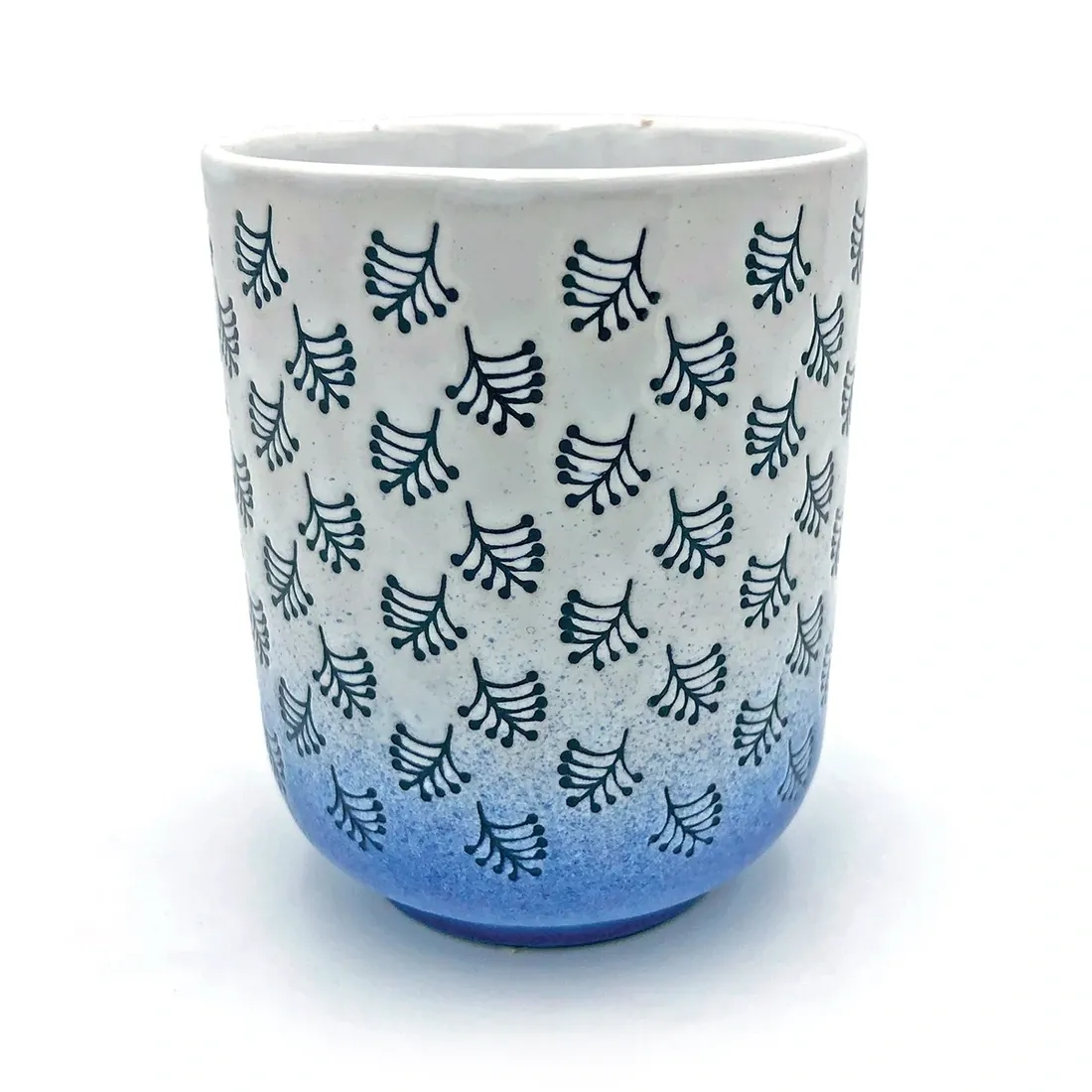 Close-up van een mok uit de witte & blauwe beker set met donkerblauwe bladmotieven en een blauw kleurverloop aan de onderkant.