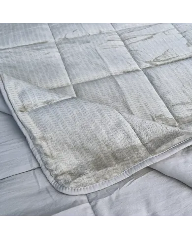 Close-up of a velvet bedspread with textured square stitching and contrasting underside.