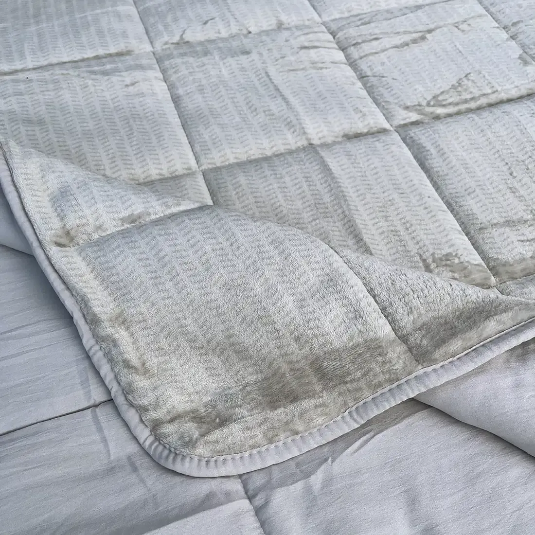 Close-up of a velvet bedspread with textured square stitching and contrasting underside.
