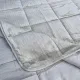 Close-up of a velvet bedspread with textured square stitching and contrasting underside.