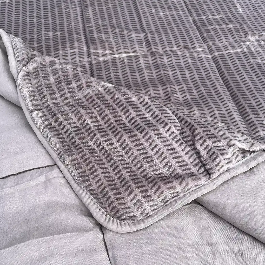 Close-up of a velvet bedspread with textured square stitching and contrasting underside.