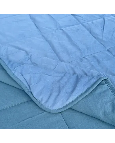 Close-up van een fluwelen dekbed zonder overtrek blauw met vierkante stiksels en een contrasterende onderkant.