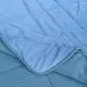 Close-up van een fluwelen dekbed zonder overtrek blauw met vierkante stiksels en een contrasterende onderkant.