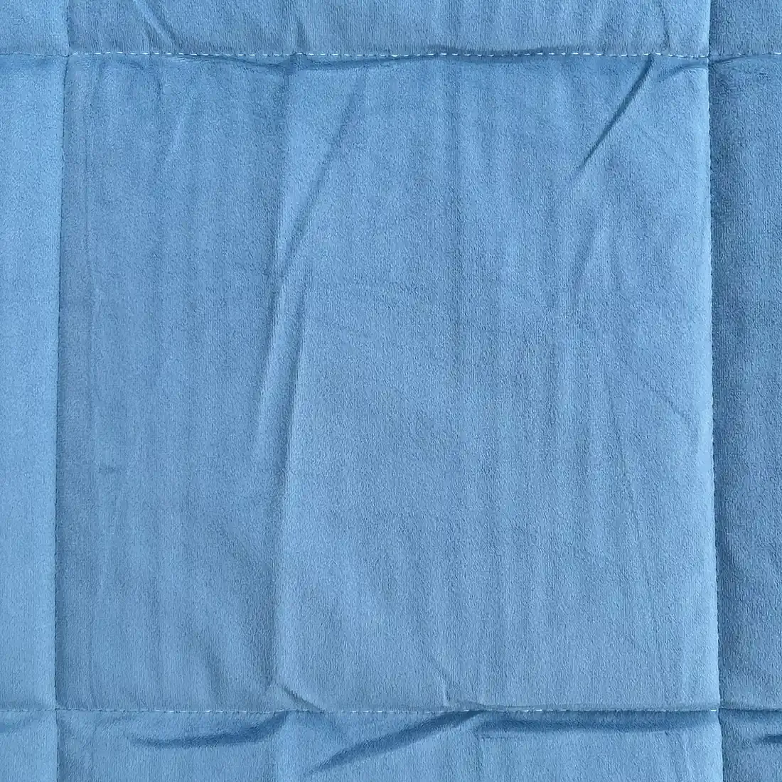 Close-up of a velvet bedspread showcasing the quilted square stitching.