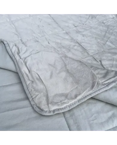 Close-up of a velvet bedspread with textured square stitching and contrasting underside.