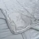 Close-up of a velvet bedspread with textured square stitching and contrasting underside.