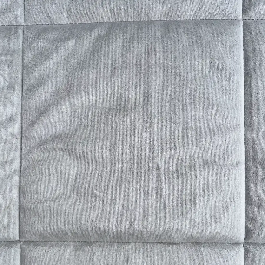 Close-up of a velvet bedspread showcasing the quilted square stitching.