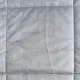 Close-up of a velvet bedspread showcasing the quilted square stitching.