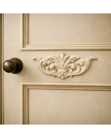 Close-up of a beige door with a decorative furniture applique and a dark bronze knob.