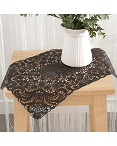 Een zwarte placemat in kant-stijl van vinyl op een houten tafel, met een witte kruikvaas gevuld met groenblad. Een zwarte placemat in kant-stijl van vinyl op een houten tafel, met een witte kruikvaas gevuld met groenblad.