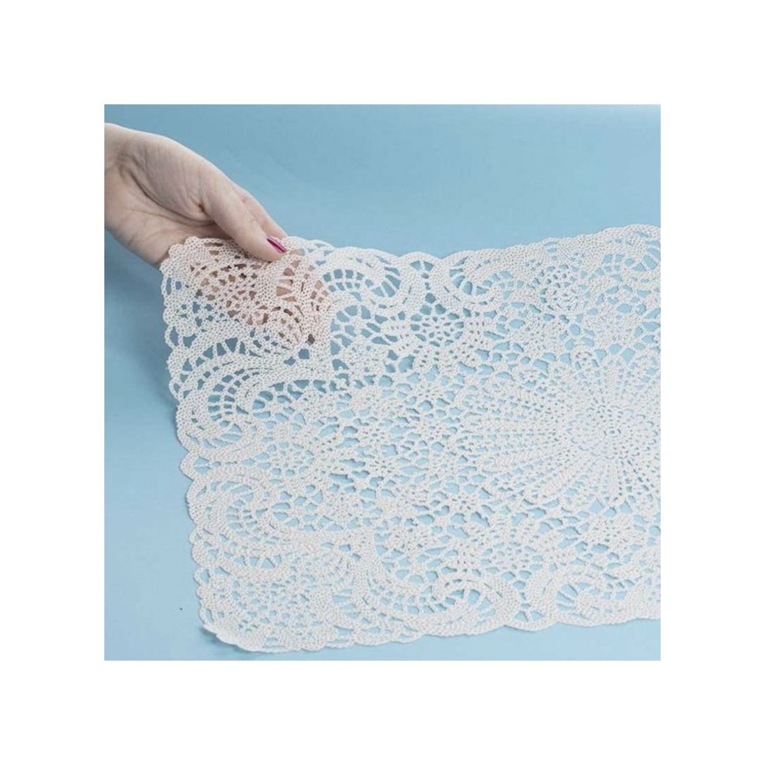 A hand holds a lace vinyl placemat, highlighting the laser-cut lace patterns.