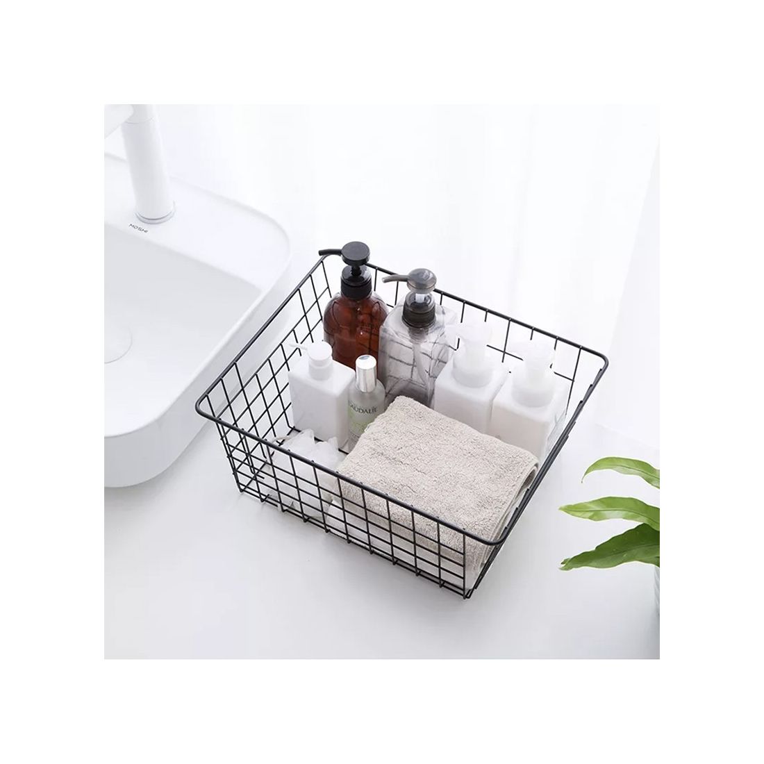 Draadmand zwart voor opberging gevuld met verschillende toiletartikelen, een handdoekje en een plant op de achtergrond. Draadmand zwart voor opberging gevuld met verschillende toiletartikelen, een handdoekje en een plant op de achtergrond.