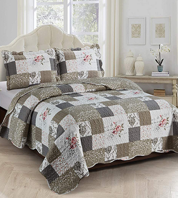 A cozy bedroom featuring a khaki brown and beige patchwork quilt with a vintage rose design